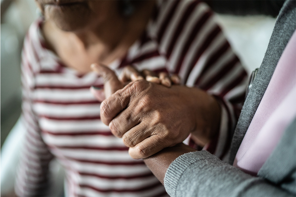 Two elderly women clasp hands